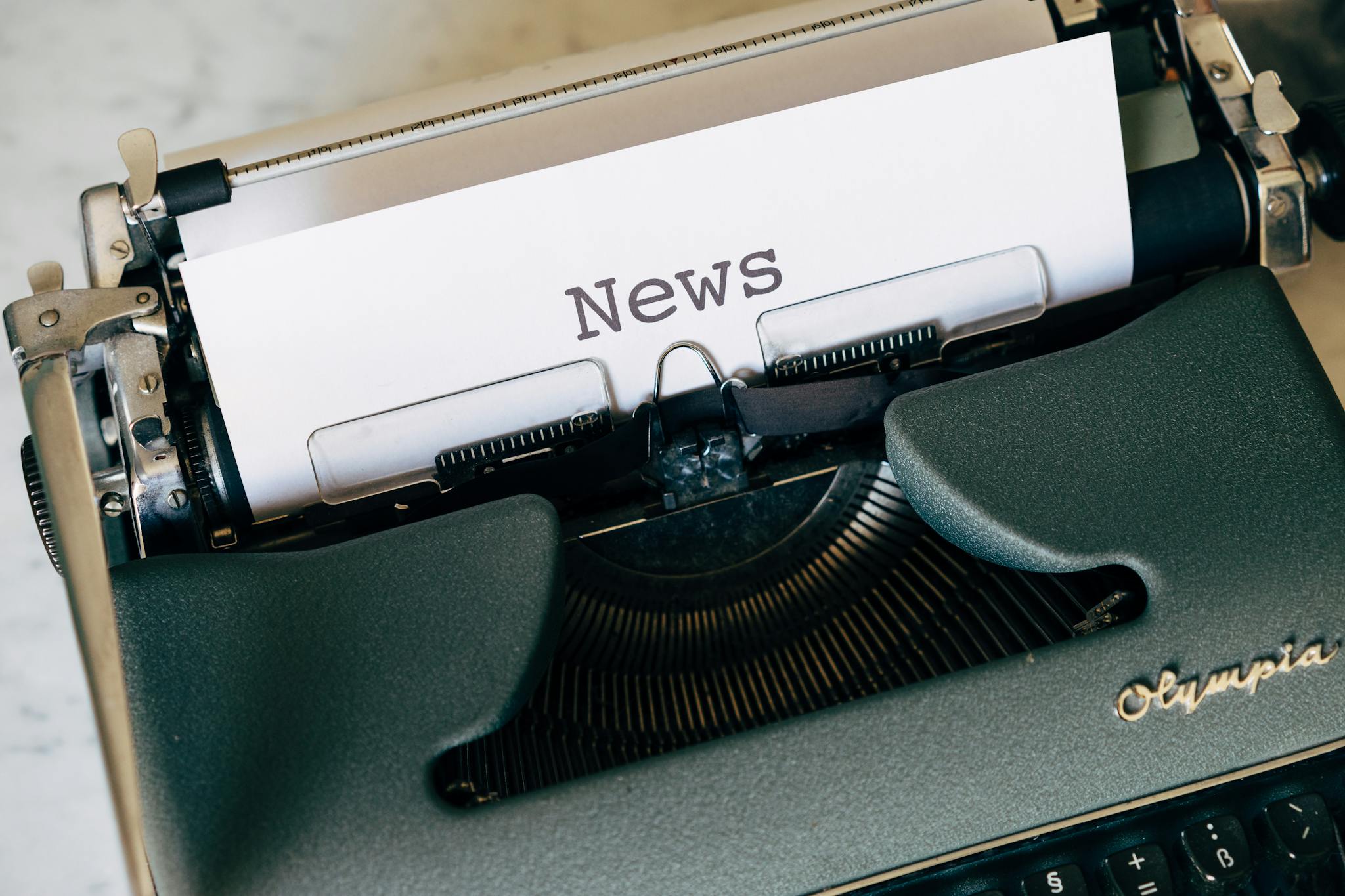 Close-up of a vintage Olympia typewriter with paper reading 'news'. Perfect for classic journalism themes.